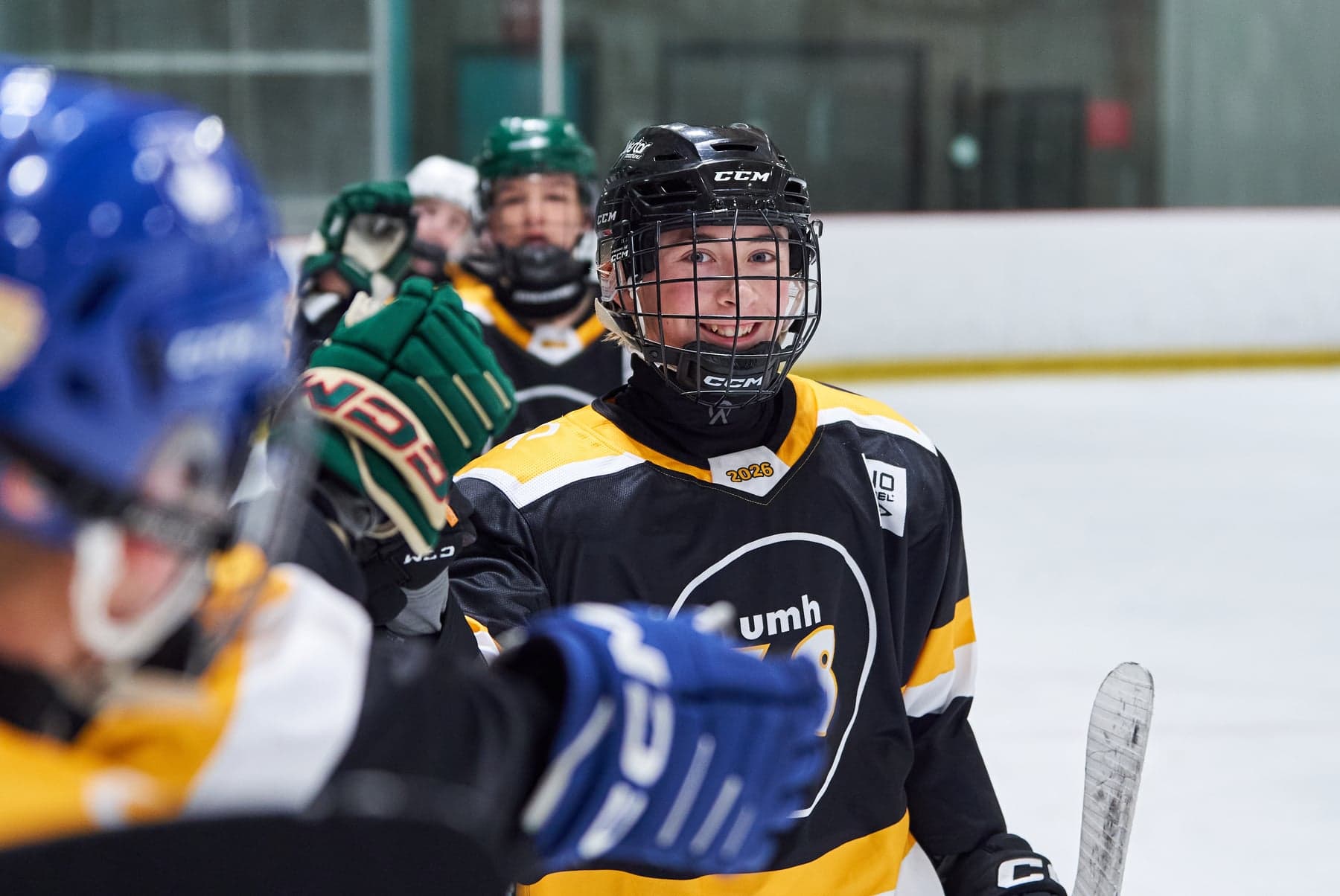 A smiling black-and-gold UMH-68 player exchanges glove bumps with teammates